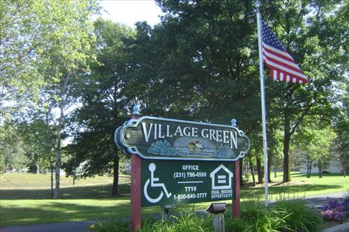 Village Green Apartments entrance hording with flag